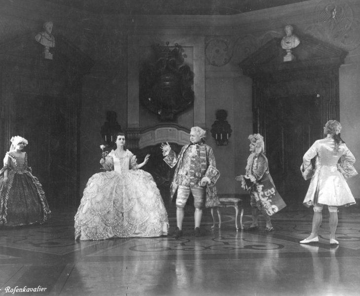 Black and white picture from the movie Der Rosenkavalier with five people in historical clothing