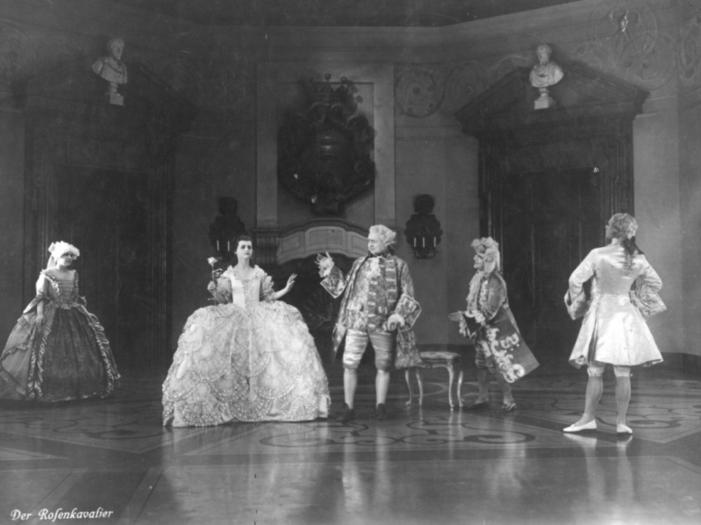 Black and white picture from the movie Der Rosenkavalier with five people in historical clothing