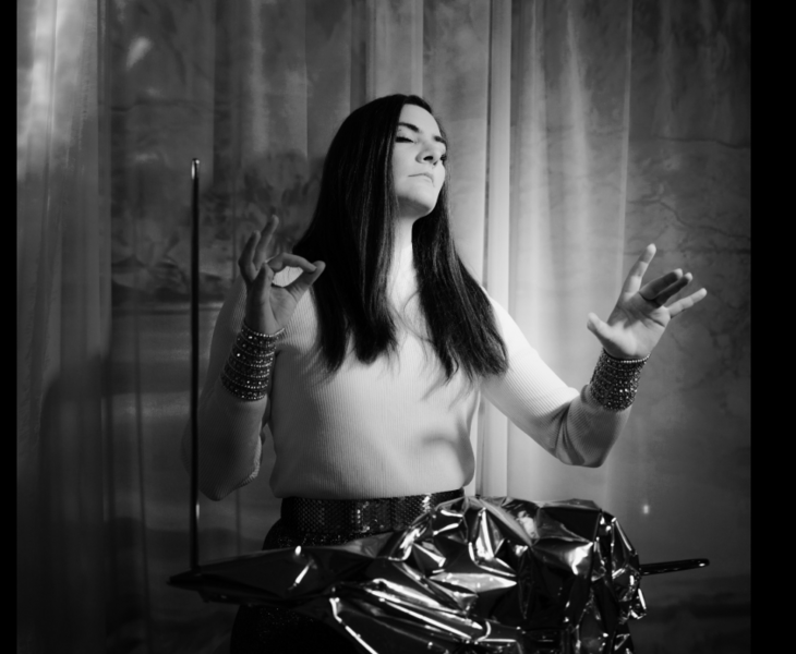 A woman with long dark hair plays the Theremin with closed eyes