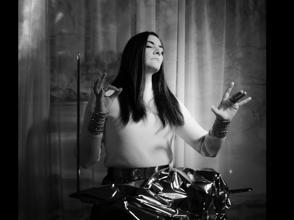 A woman with long dark hair plays the Theremin with closed eyes