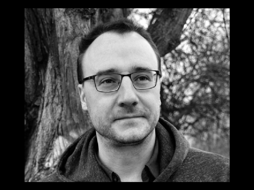 A man with short hair and glasses